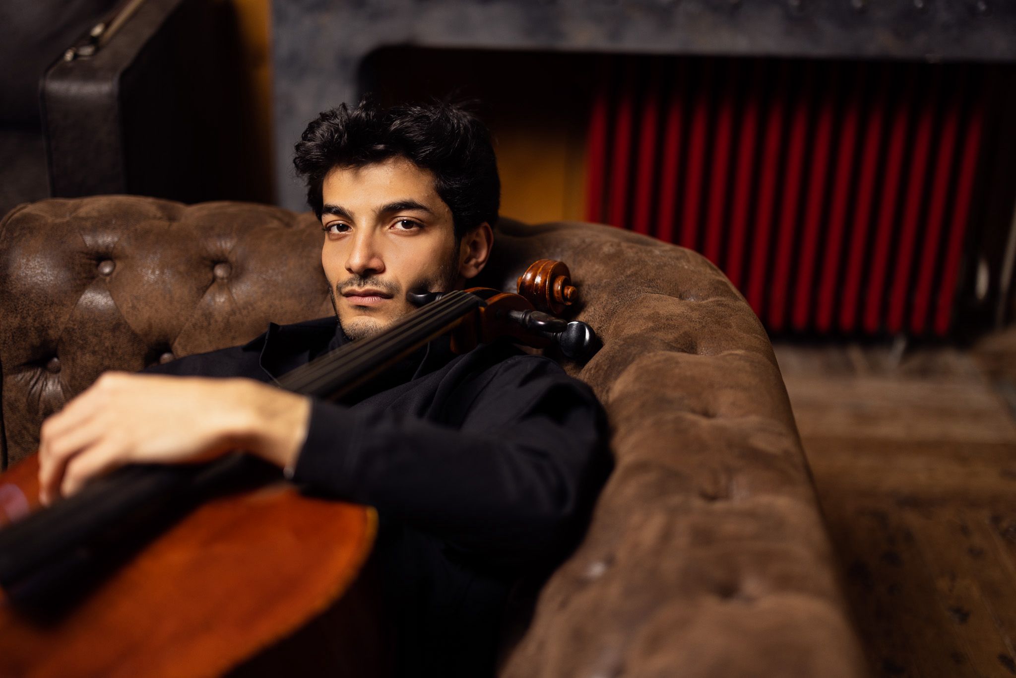 Portrait of Yunus Altıkanat with his cello on a leather sofa